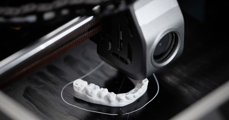 A close-up view of a 3D printer producing a detailed orthodontic dental model, showcasing advanced digital dentistry technology.